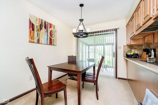 dining room featuring light colored carpet, baseboards, and a chandelier
