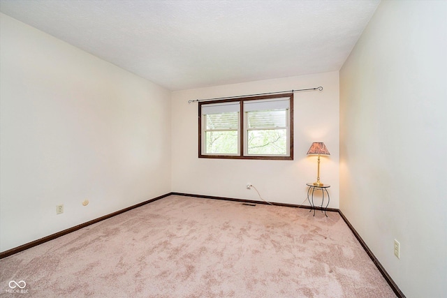 spare room with baseboards and carpet floors