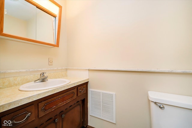 bathroom with vanity, toilet, backsplash, and visible vents