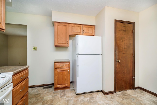 kitchen featuring freestanding refrigerator, baseboards, visible vents, and range