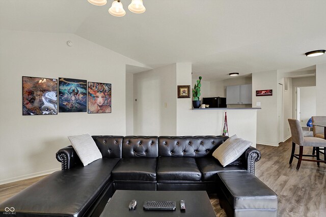 living area with baseboards, vaulted ceiling, and wood finished floors
