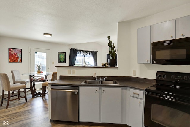 kitchen with black appliances, dark countertops, and plenty of natural light