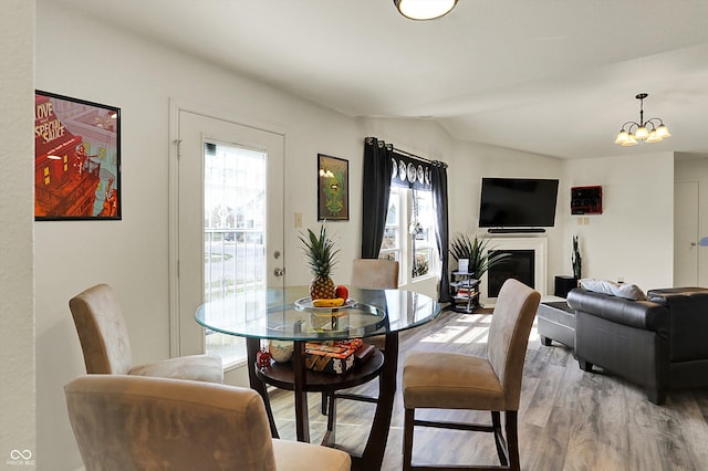 dining room with vaulted ceiling, wood finished floors, a chandelier, and a healthy amount of sunlight