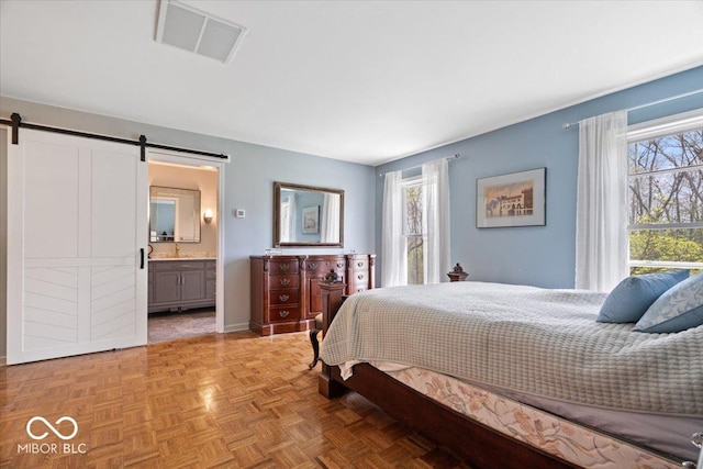 bedroom with visible vents, a barn door, connected bathroom, and multiple windows