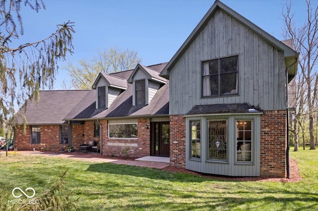 view of front of property featuring brick siding, a patio, and a front lawn