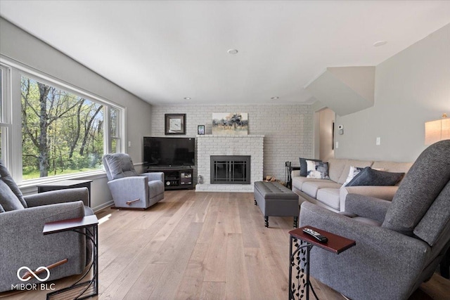 living room with a brick fireplace and light wood-type flooring