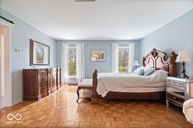 bedroom with baseboards, a barn door, and visible vents