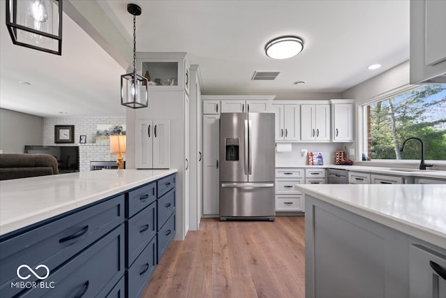 kitchen featuring visible vents, light countertops, white cabinetry, stainless steel fridge with ice dispenser, and a sink