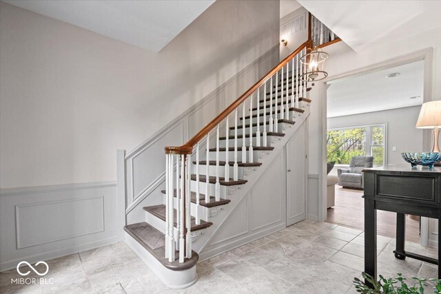 staircase featuring a decorative wall and a wainscoted wall