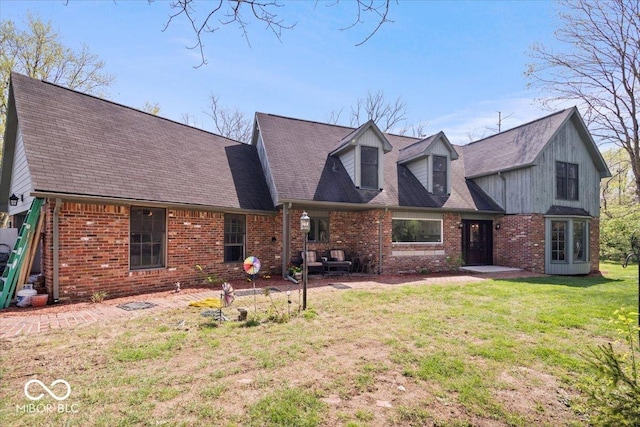 view of front facade featuring a shingled roof, a front yard, and brick siding