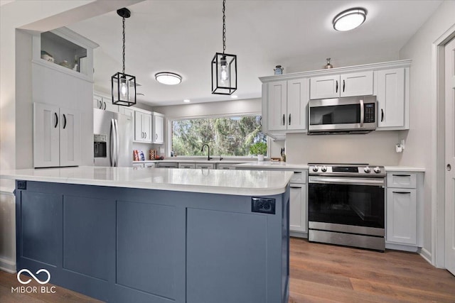 kitchen with light countertops, stainless steel appliances, dark wood finished floors, and white cabinetry