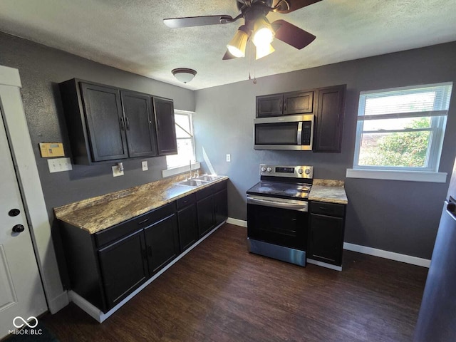 2819 W 16th St, Indianapolis, IN 46222 - kitchen featuring dark wood-style flooring, a sink, a textured ceiling, stainless steel appliances, and baseboards
