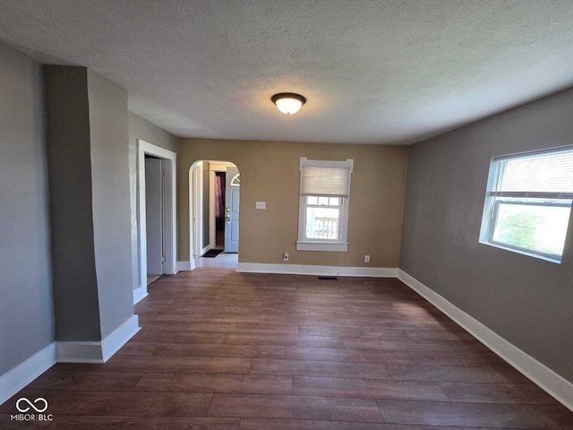 2819 W 16th St, Indianapolis, IN 46222 - unfurnished room with dark wood-type flooring, arched walkways, a textured ceiling, and baseboards