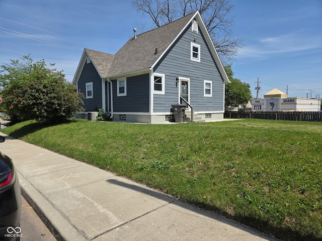 2819 W 16th St, Indianapolis, IN 46222 - view of side of property featuring a yard, fence, a shingled roof, and entry steps