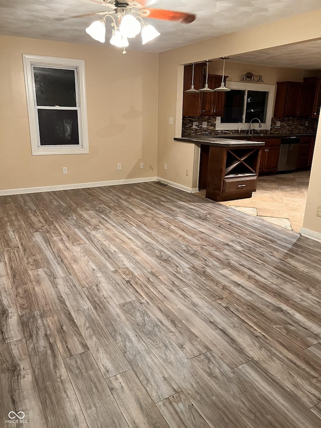 interior space with dark countertops, stainless steel dishwasher, ceiling fan, and light wood-type flooring