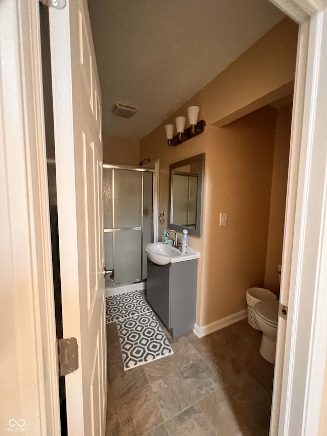 bathroom with toilet, vanity, visible vents, a shower stall, and stone finish flooring