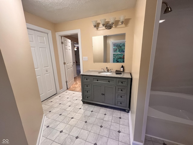 bathroom featuring a bathtub, a textured ceiling, baseboards, tile patterned flooring, and vanity