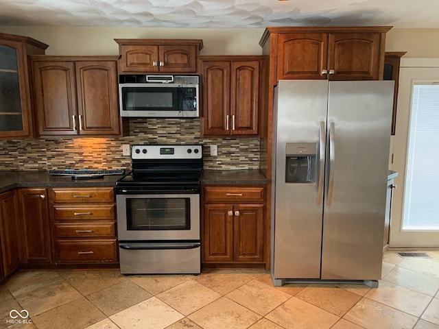 kitchen with backsplash, dark countertops, appliances with stainless steel finishes, and glass insert cabinets
