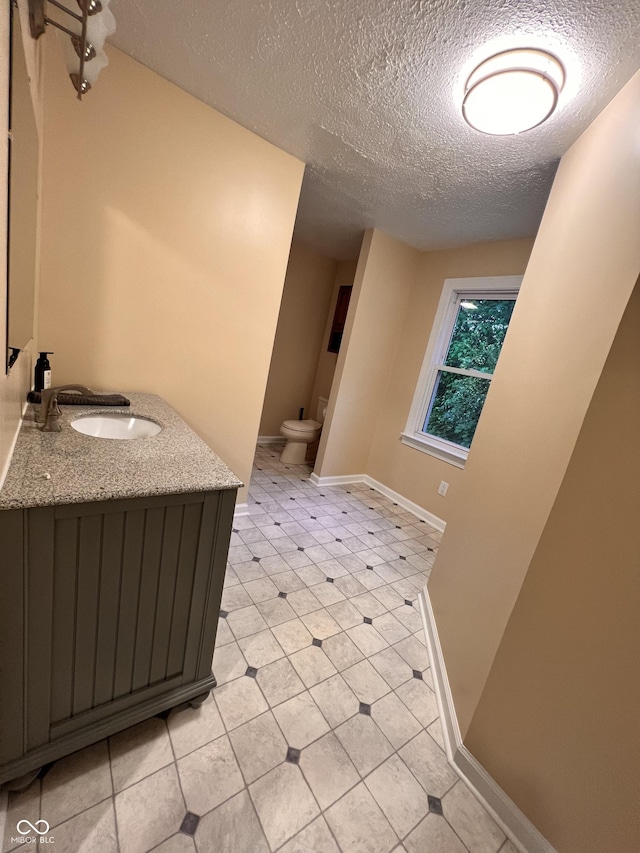 bathroom with a textured ceiling, baseboards, toilet, and tile patterned flooring