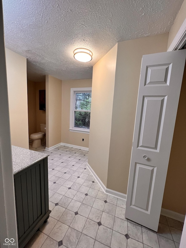 hall featuring a textured ceiling and baseboards