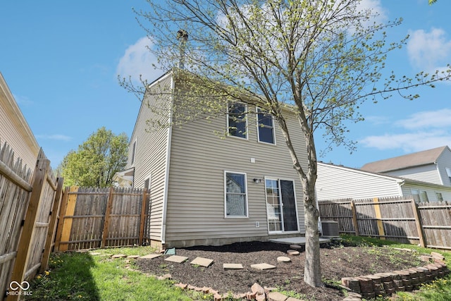 rear view of property with central air condition unit and a fenced backyard