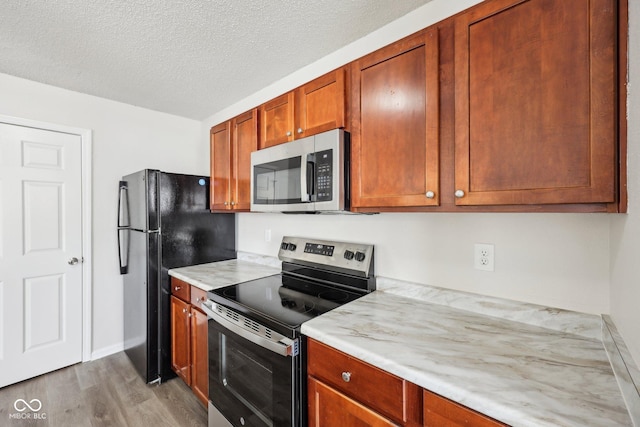 kitchen featuring stainless steel appliances, a textured ceiling, and wood finished floors