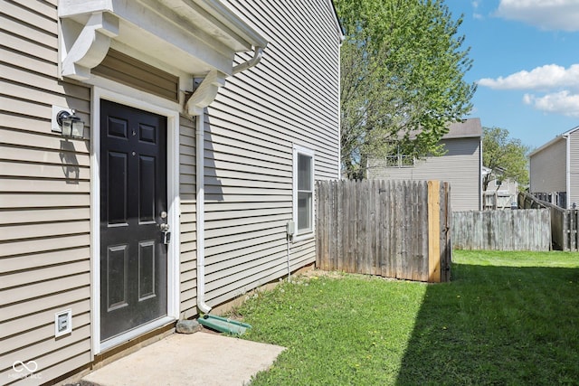 entrance to property featuring a yard and fence
