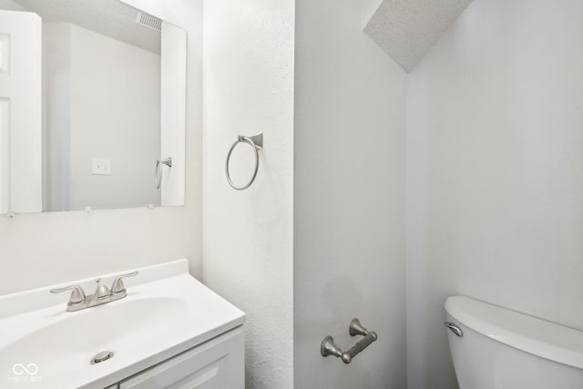 bathroom with toilet, visible vents, and vanity