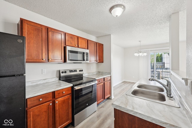 kitchen featuring a sink, appliances with stainless steel finishes, light wood finished floors, and light countertops
