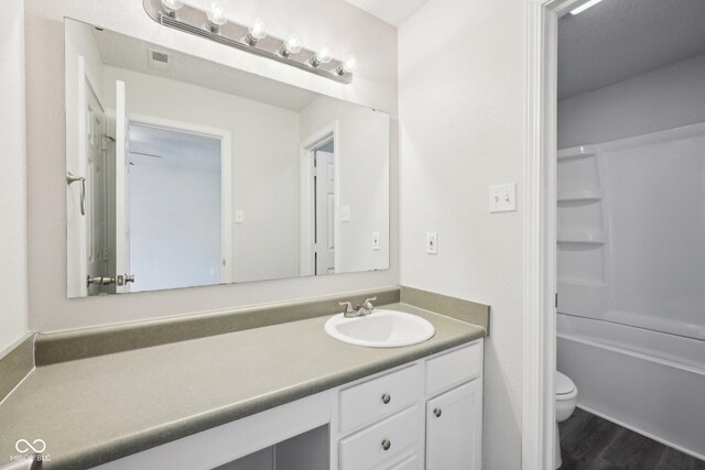 full bathroom with shower / tub combination, vanity, toilet, wood finished floors, and visible vents