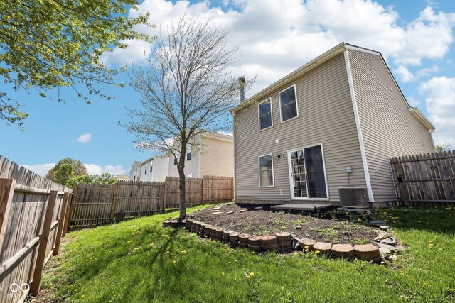 back of house with a fenced backyard and a yard