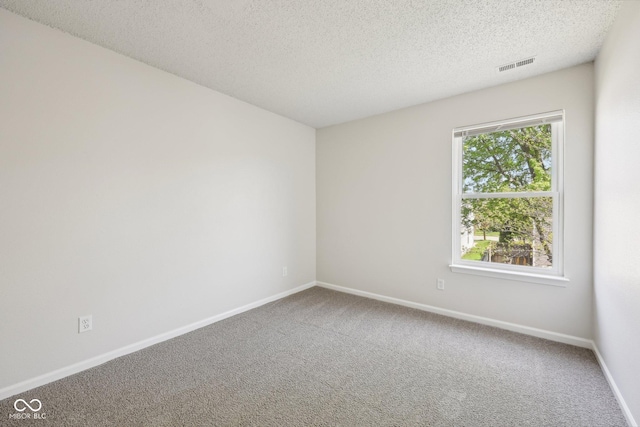 empty room with carpet floors, a textured ceiling, visible vents, and baseboards
