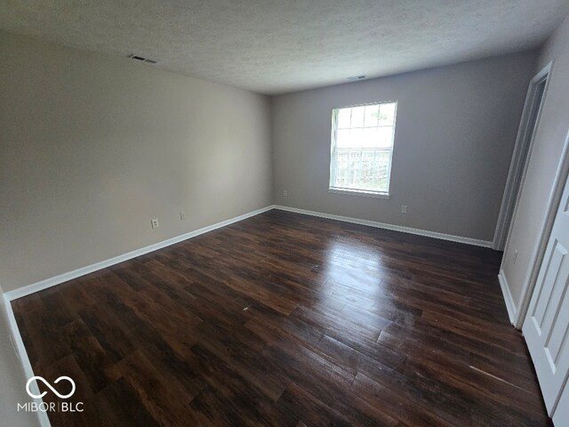 9118 Lansburgh Ct, Indianapolis, IN 46234 - unfurnished room featuring baseboards, visible vents, a textured ceiling, and dark wood-style floors