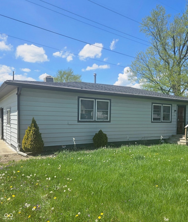 view of side of property featuring a lawn and a chimney