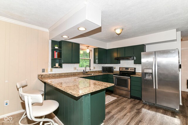 7140 Avalon Trail Dr, Indianapolis, IN 46250 - kitchen featuring stainless steel appliances, green cabinets, a peninsula, under cabinet range hood, and tasteful backsplash