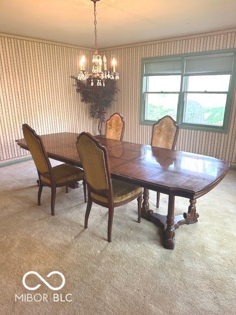 carpeted dining area featuring wallpapered walls and a notable chandelier