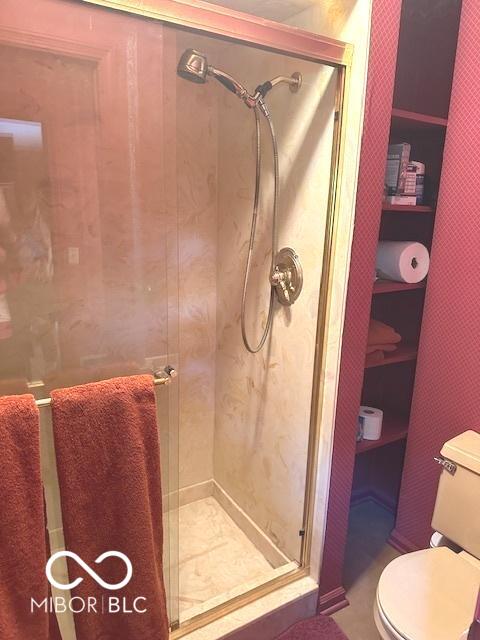 bathroom featuring toilet and a stall shower