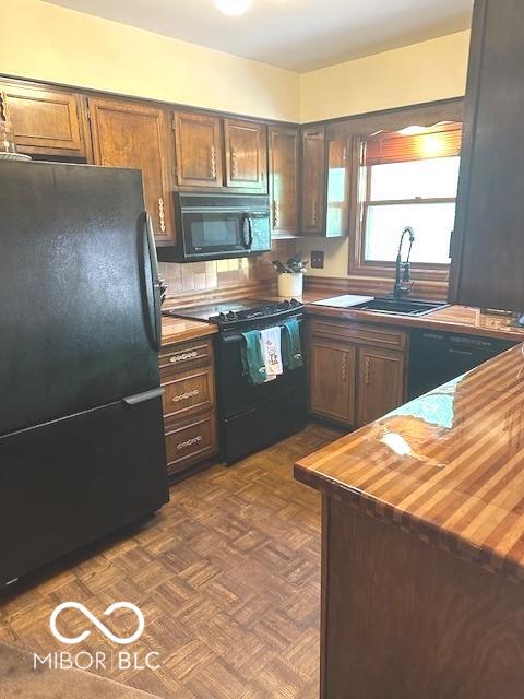 kitchen with a sink, wood counters, and black appliances
