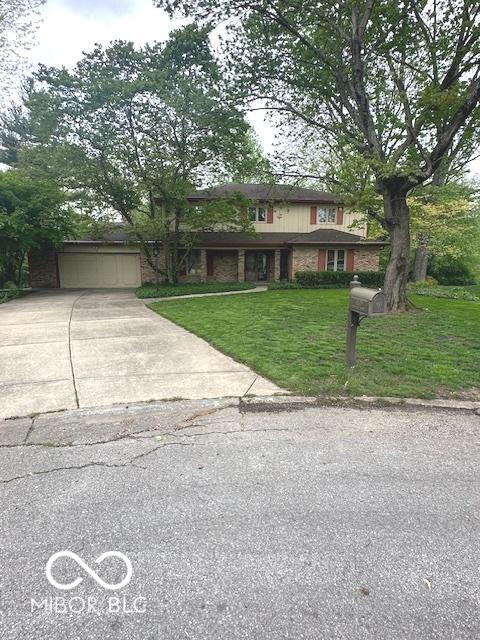 traditional-style home with a garage, concrete driveway, and a front yard