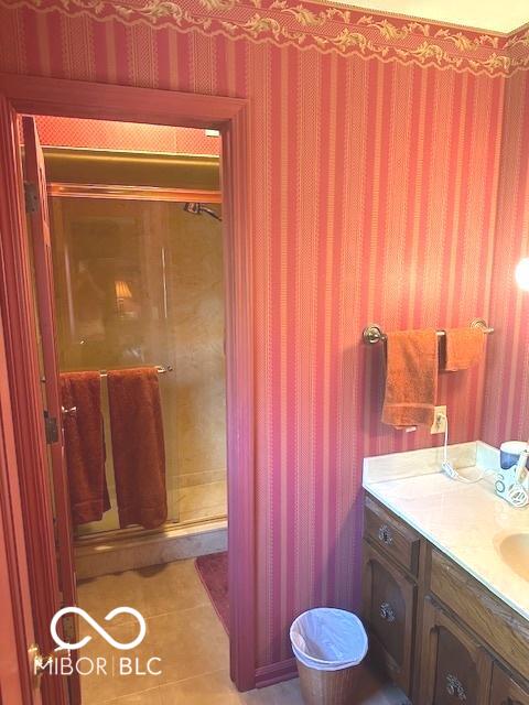 full bathroom featuring tile patterned flooring, wallpapered walls, vanity, and a shower stall