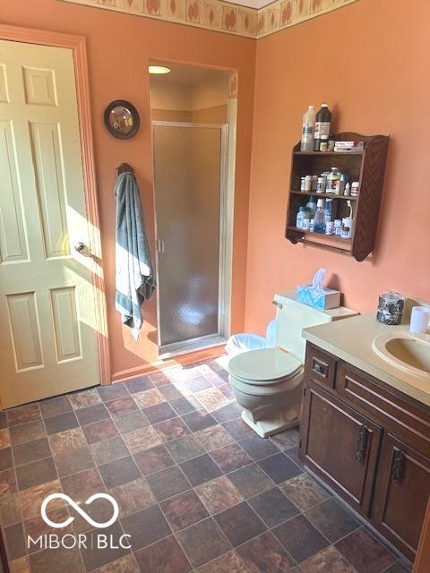 full bathroom featuring vanity, stone finish floor, toilet, and a shower stall
