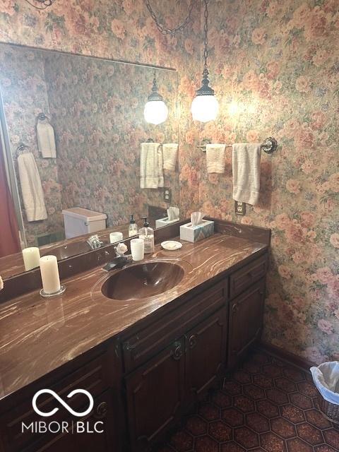 bathroom featuring toilet, wallpapered walls, baseboards, and vanity