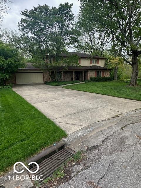 view of front of house featuring a garage, concrete driveway, a front lawn, and brick siding
