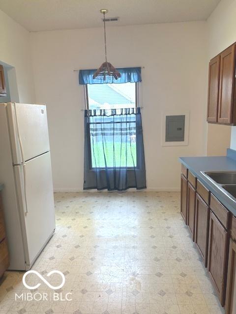 kitchen with freestanding refrigerator, light floors, baseboards, and visible vents