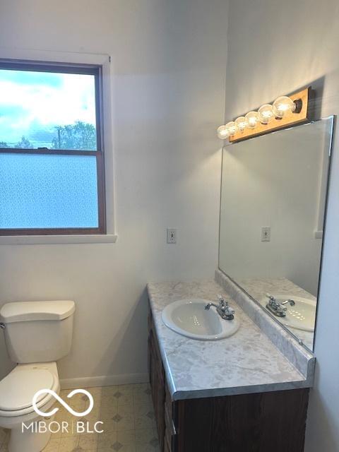 bathroom with baseboards, vanity, and toilet