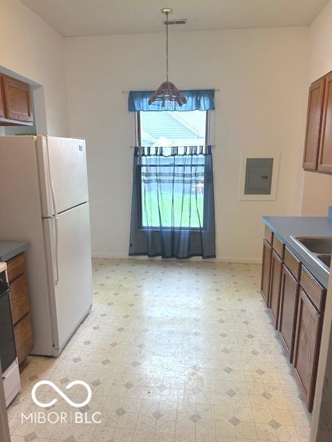 kitchen featuring freestanding refrigerator, light floors, baseboards, and a sink