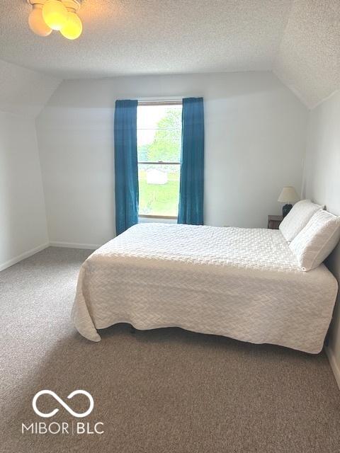carpeted bedroom featuring a textured ceiling, baseboards, and lofted ceiling