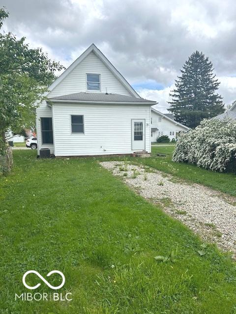 rear view of property featuring a lawn and central AC unit