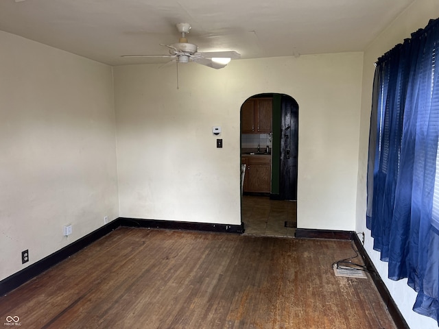 3434 Forrest Ter, Anderson Se, IN 46013 - unfurnished room featuring arched walkways, wood finished floors, a sink, baseboards, and a ceiling fan