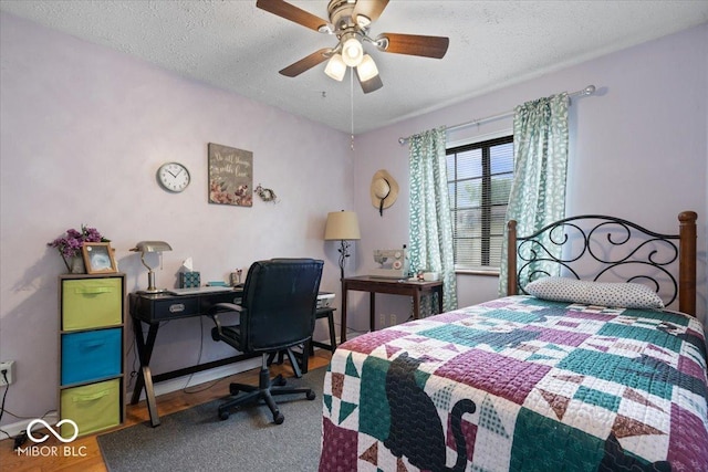 bedroom with a ceiling fan, a textured ceiling, and wood finished floors